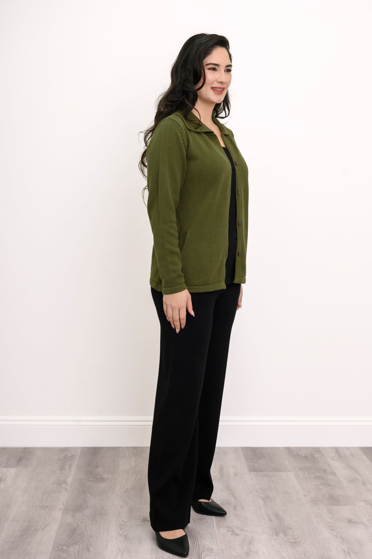 Side view of a woman in a comfortable green collared sweater displaying a fitted silhouette with natural stretch.