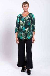 Woman facing forward in green floral bamboo top and black pants, neutral expression