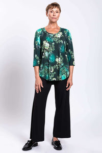 Woman standing in green floral bamboo top and black pants, full body, white background