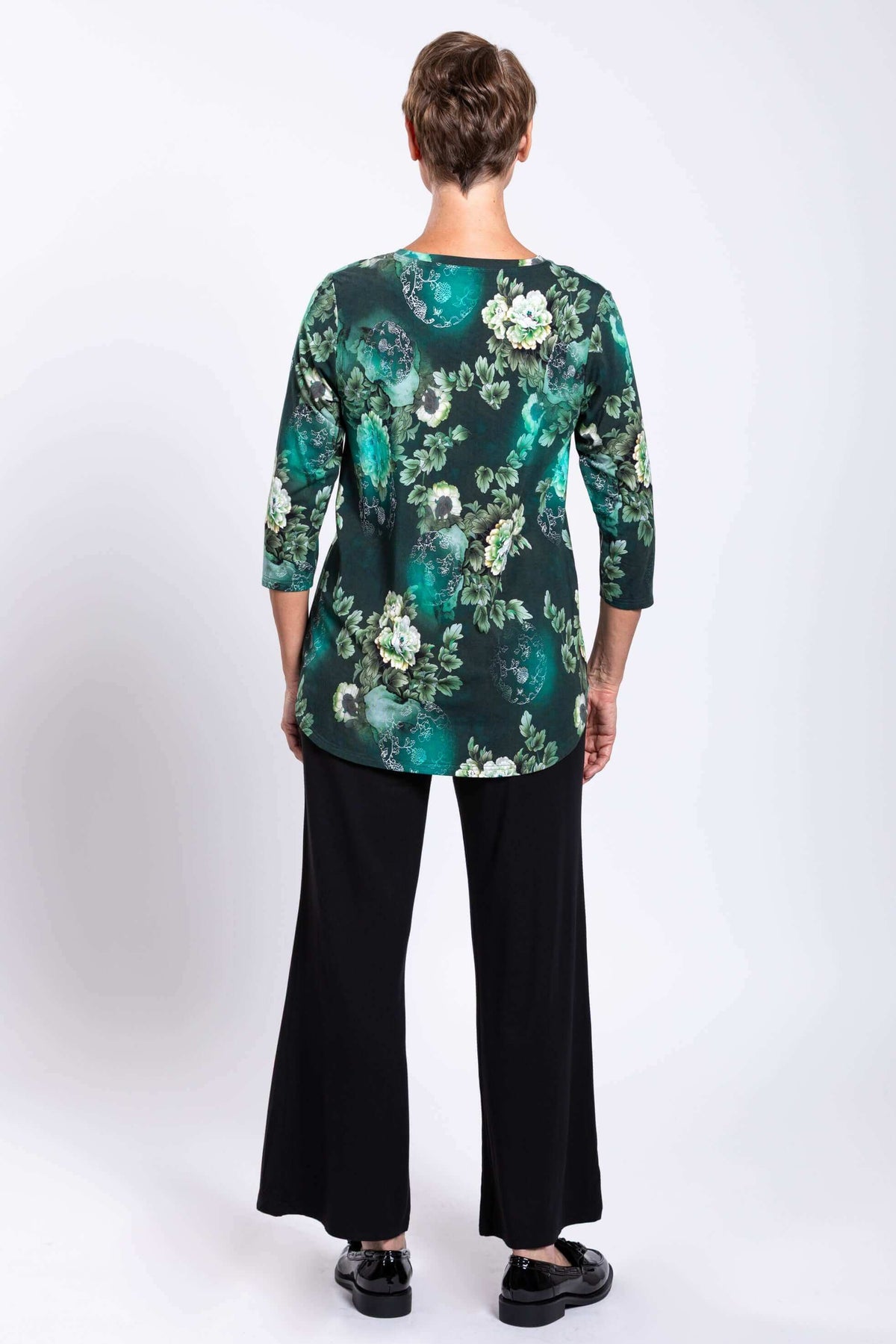 Back view of woman wearing green floral bamboo top with 3/4 sleeves and black pants