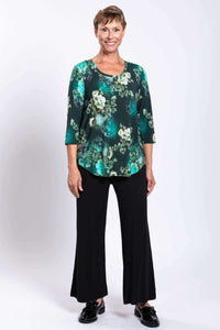 Woman modeling a green floral bamboo top with black pants, full front view, smiling
