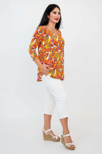 Diagonal front view of a woman in a colorful leaf print bamboo top and white pants
