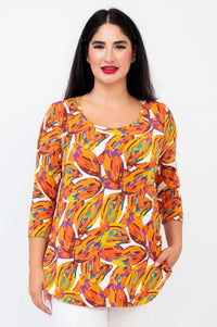 Front view of a woman wearing a vibrant orange leaf print 3/4 sleeve bamboo top