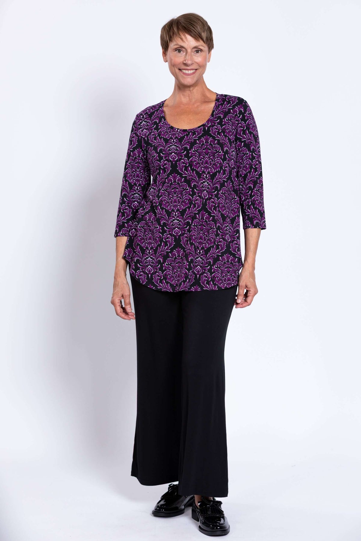 Woman wearing Jazz 3/4 Sleeve Top in Damask Purple with black wide-leg pants