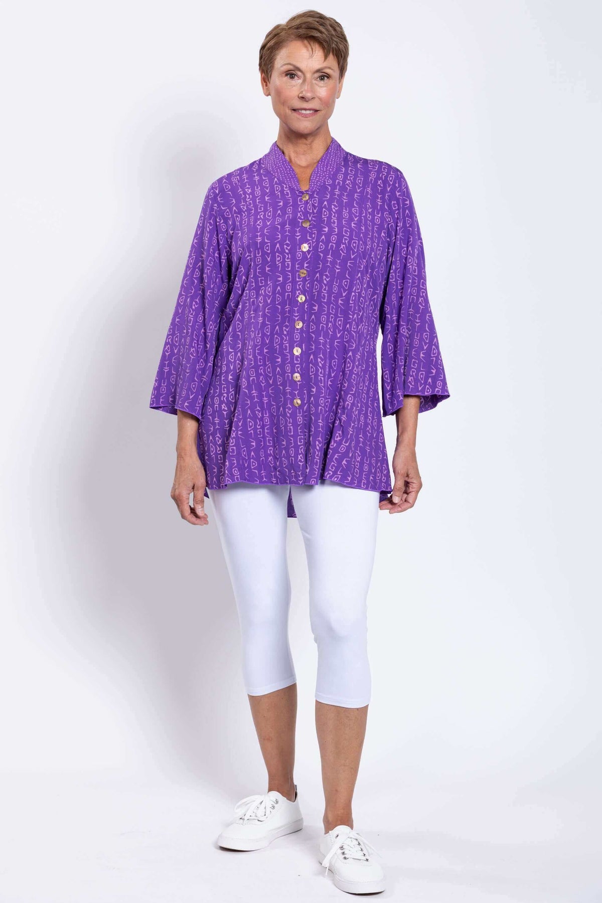 Woman modeling purple Mar blouse with white leggings, standing full length