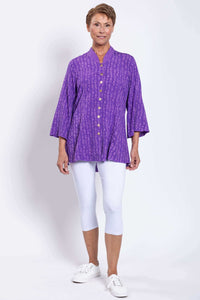 Woman modeling purple Mar blouse with white leggings, standing full length