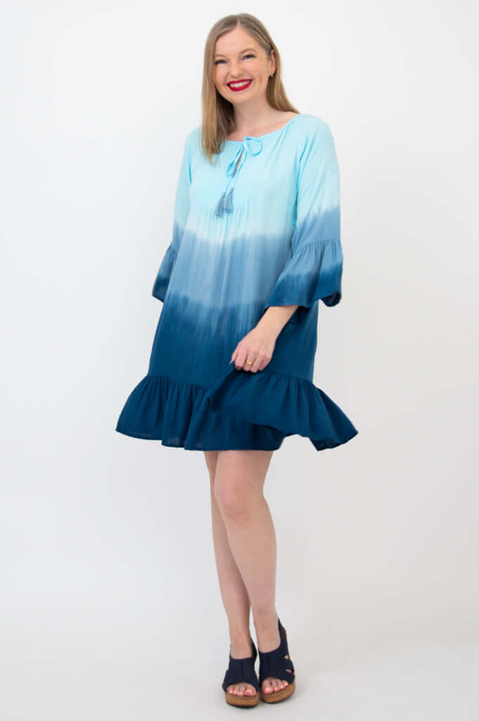 Smiling model in a blue ombre Ellie Dress with flounce hem and 3/4 ruffled sleeves