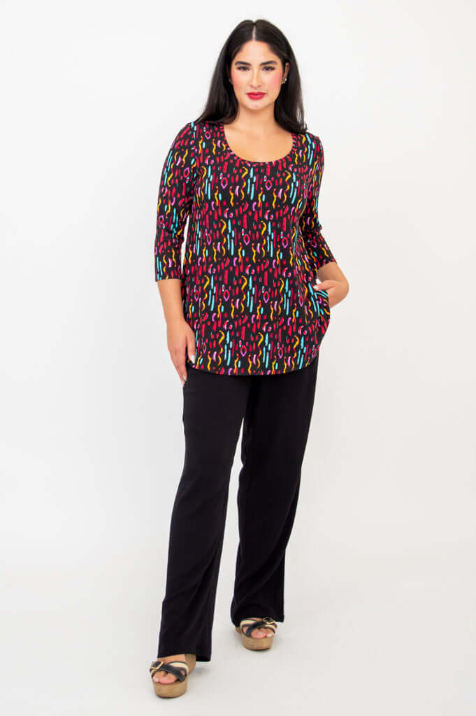 Model standing with hand in pocket wearing Jazz 3/4 sleeve abstract print top and black pants