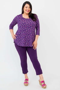 Full body view of woman in purple floral 3/4 sleeve top and matching purple pants
