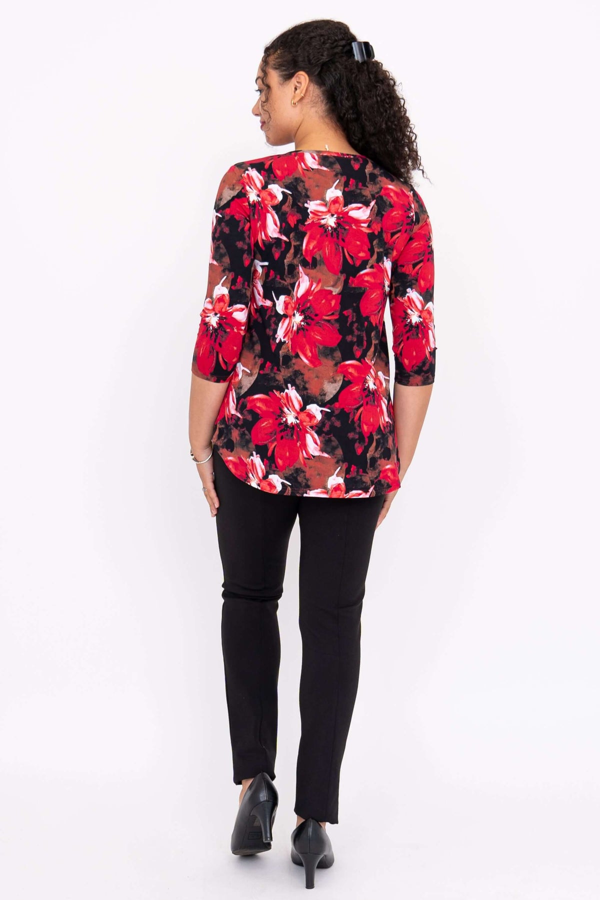 Back view of a model wearing a red floral 3/4 sleeve bamboo top with black pants