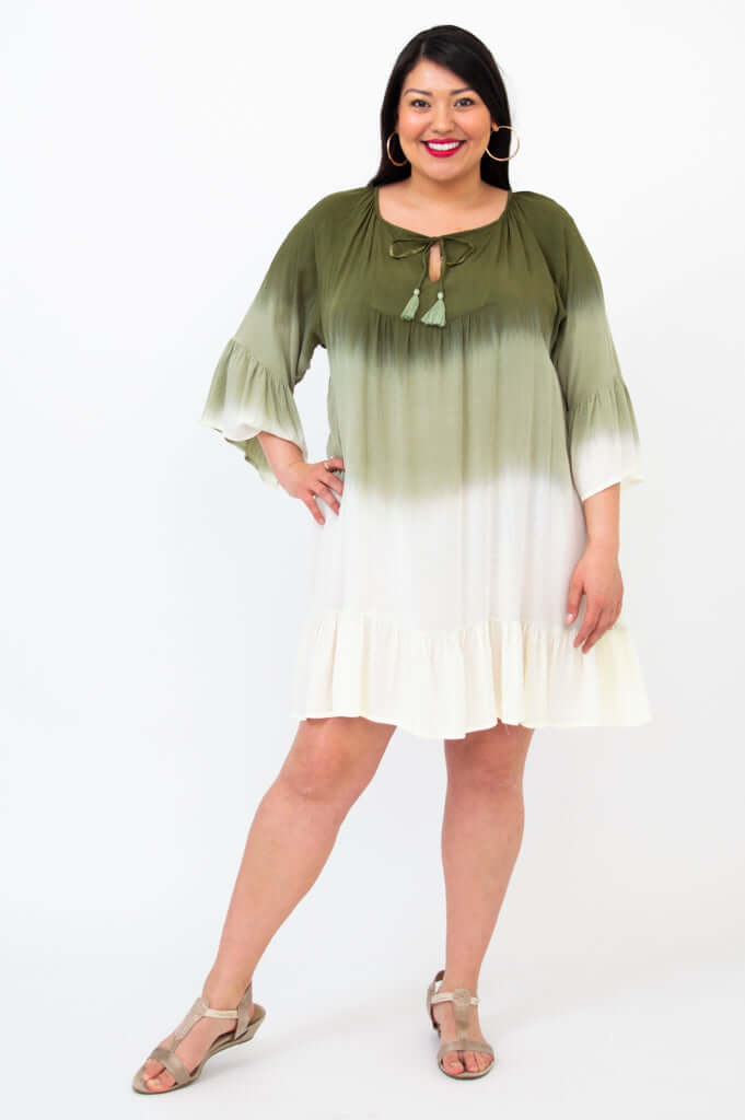 Woman wearing an olive green to white ombre dress with 3/4 ruffled sleeves and tassel tie