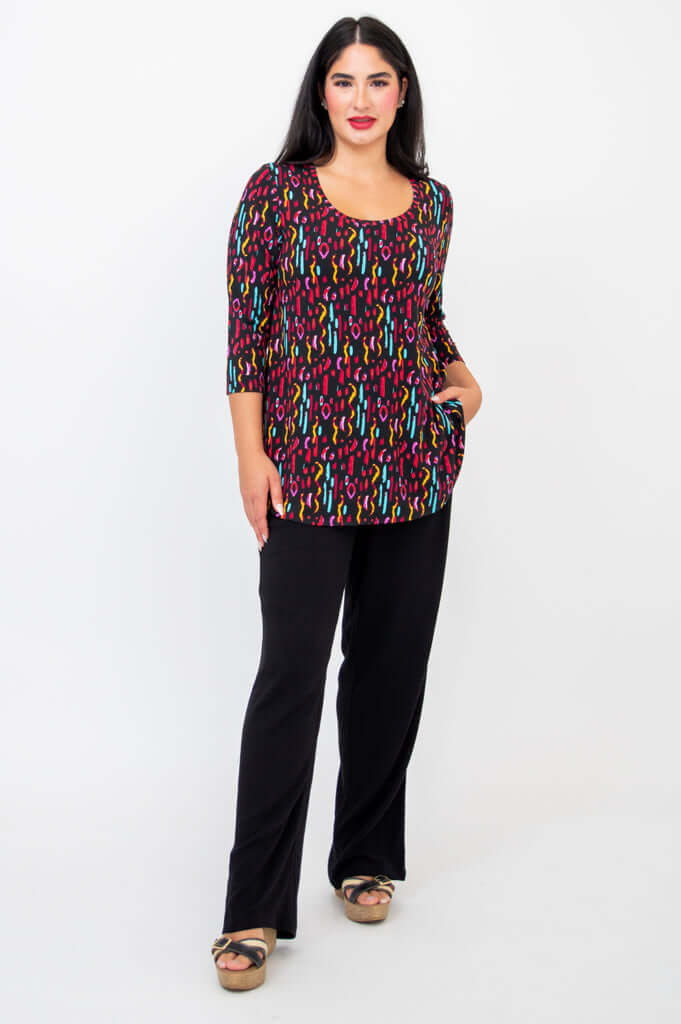 Model with both hands in pockets wearing Jazz 3/4 sleeve colorful print top and black pants