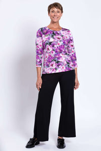 Woman in floral 3/4 sleeve top and black flare pants, smiling