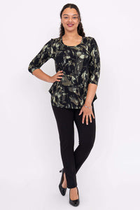 Woman standing with hand on hip in black pants and bamboo print 3/4 sleeve top