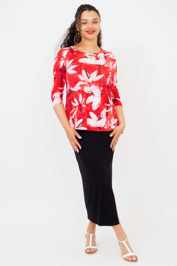 Full-body view of a model in a red floral top and black skirt with white sandals