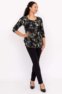 Full body view of a woman in black pants and a black and olive print 3/4 sleeve top