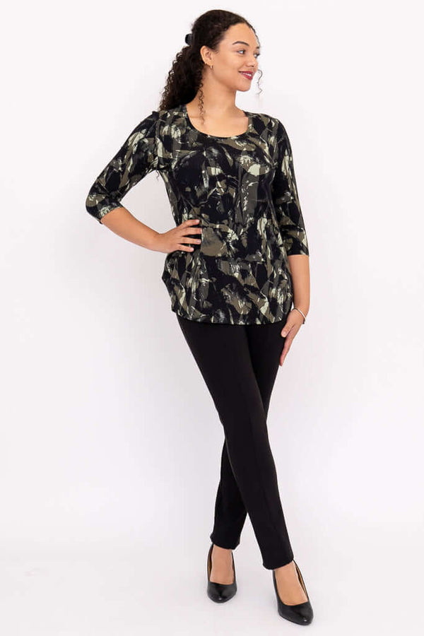 Full body view of a woman in black pants and a black and olive print 3/4 sleeve top