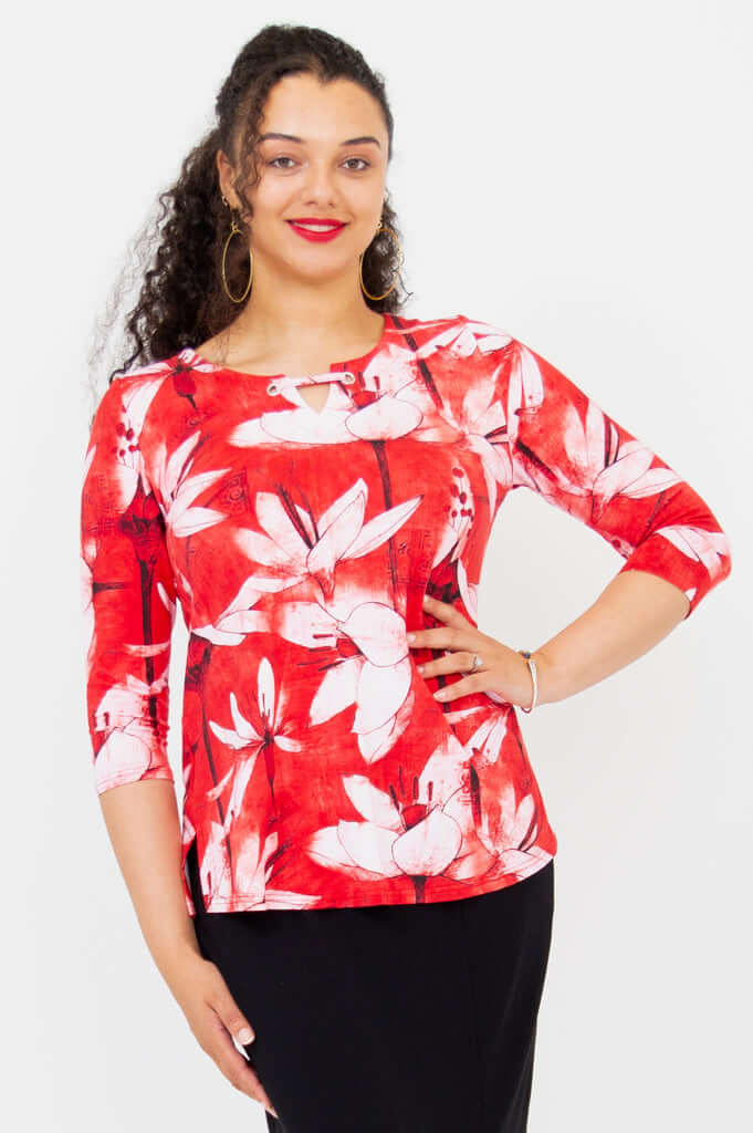Woman wearing a red and white floral 3/4 sleeve top with wide neckline and grommet detail