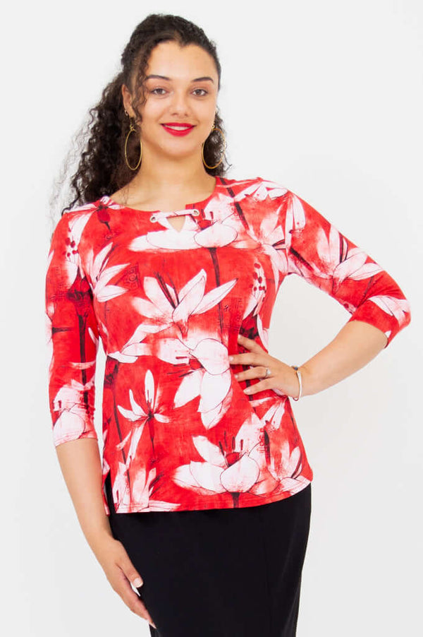 Woman wearing a red and white floral 3/4 sleeve top with wide neckline and grommet detail
