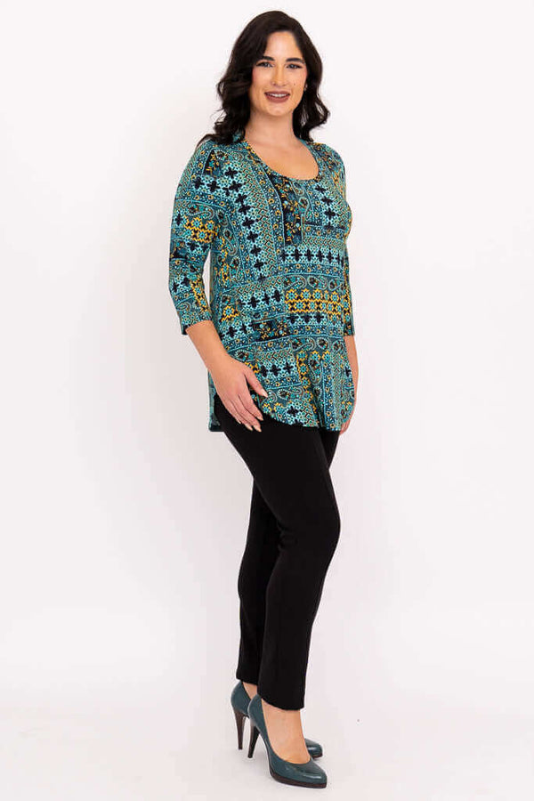 Woman showing side angle of turquoise mosaic 3/4 sleeve top with black pants