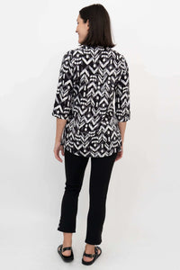 Back view of black and white smocked blouse with 3/4 sleeves and pleating, model standing