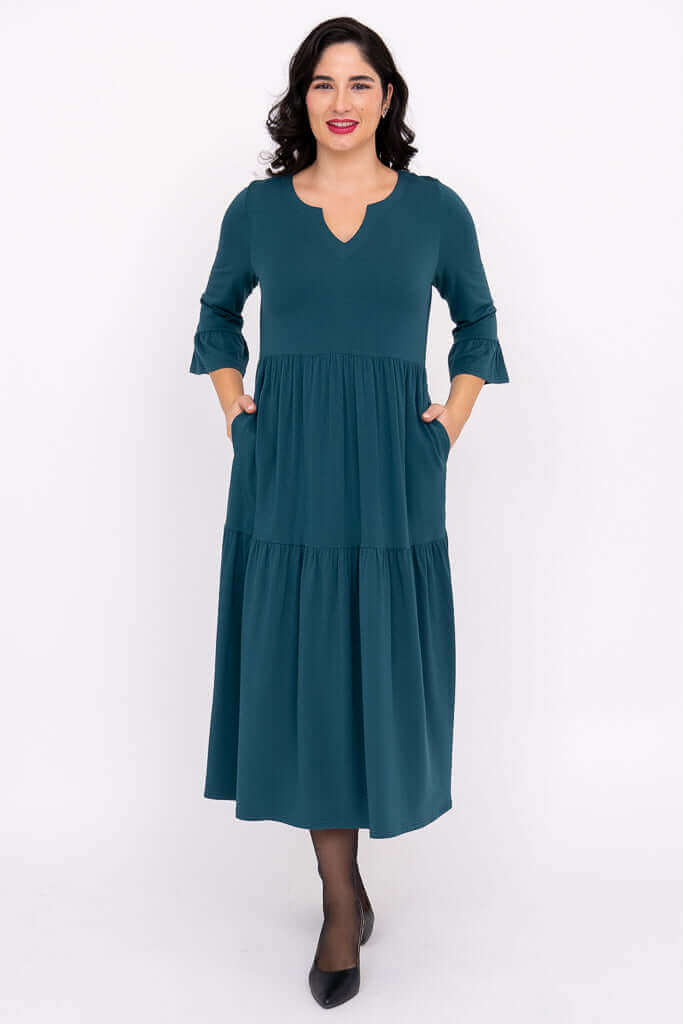 Front view of a woman in a teal, tiered midi dress with 3/4 ruffled sleeves