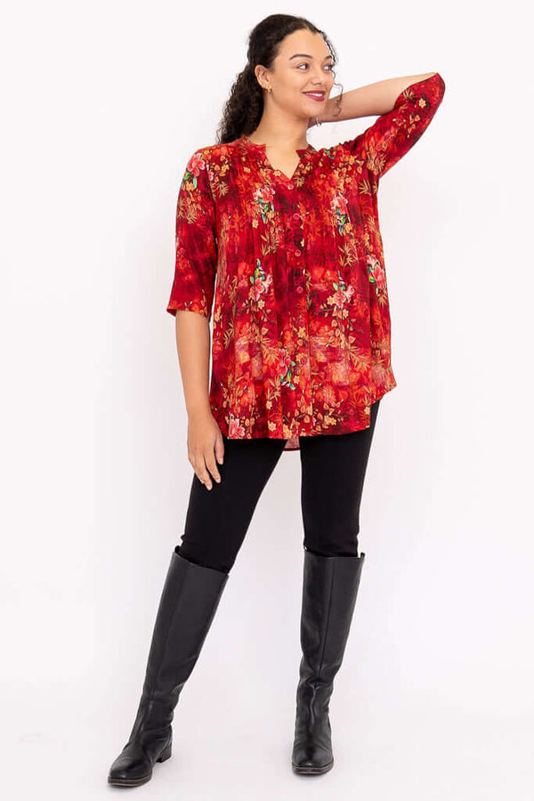 Model posing in Margate red floral blouse, one arm raised, showing button front and 3/4 sleeves