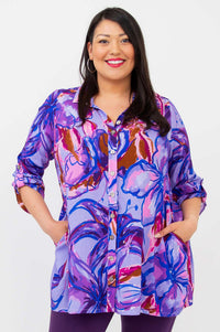 Front view of model wearing oversized button-up tunic in purple floral Painted Iris print