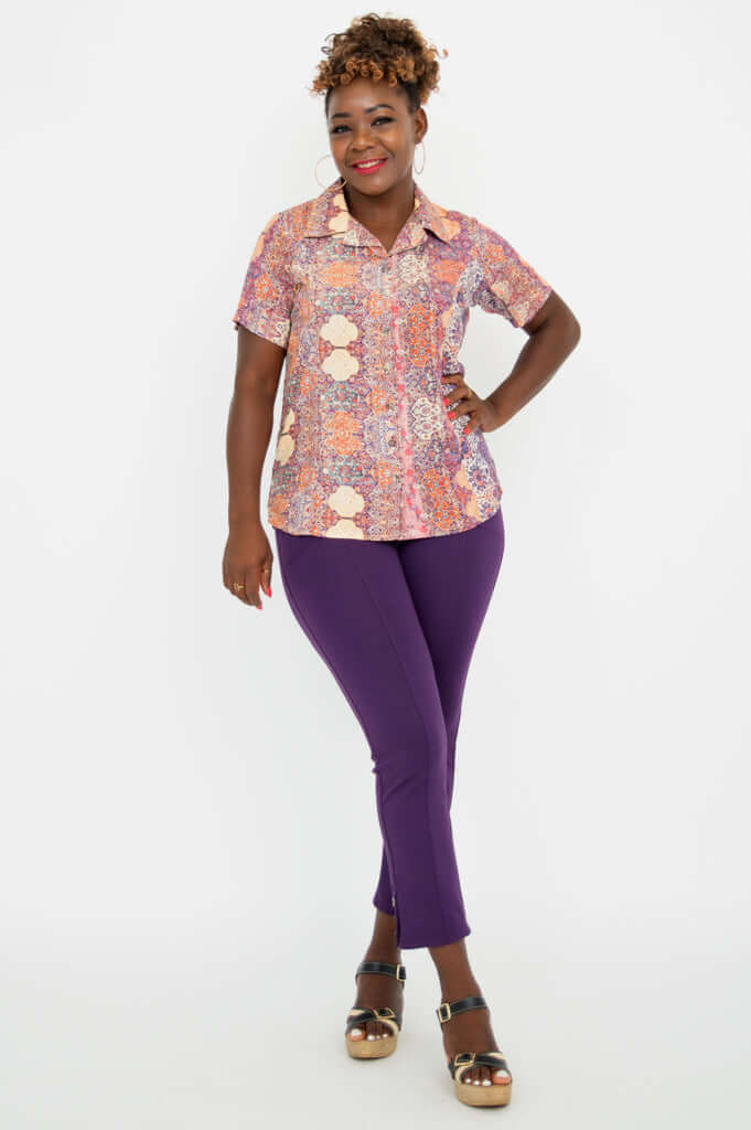 Full body view of woman in Aida Top and purple pants smiling