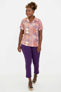 Woman walking and smiling in Aida Top paired with purple pants and sandals