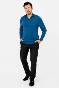 Man casually posing in blue 1/4 zip mock neck sweater and black pants