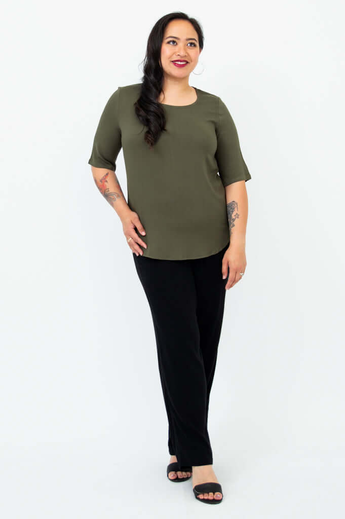 Angle view of a woman wearing an olive green blouse with black pants and sandals