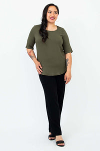 Angle view of a woman wearing an olive green blouse with black pants and sandals