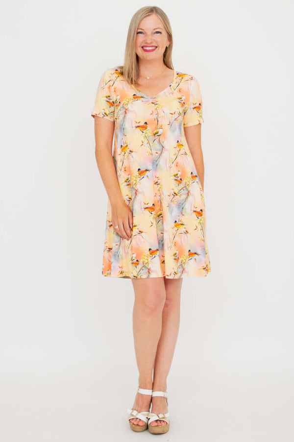 Woman in short-sleeved V-neck bamboo dress with vibrant bird pattern, front angle