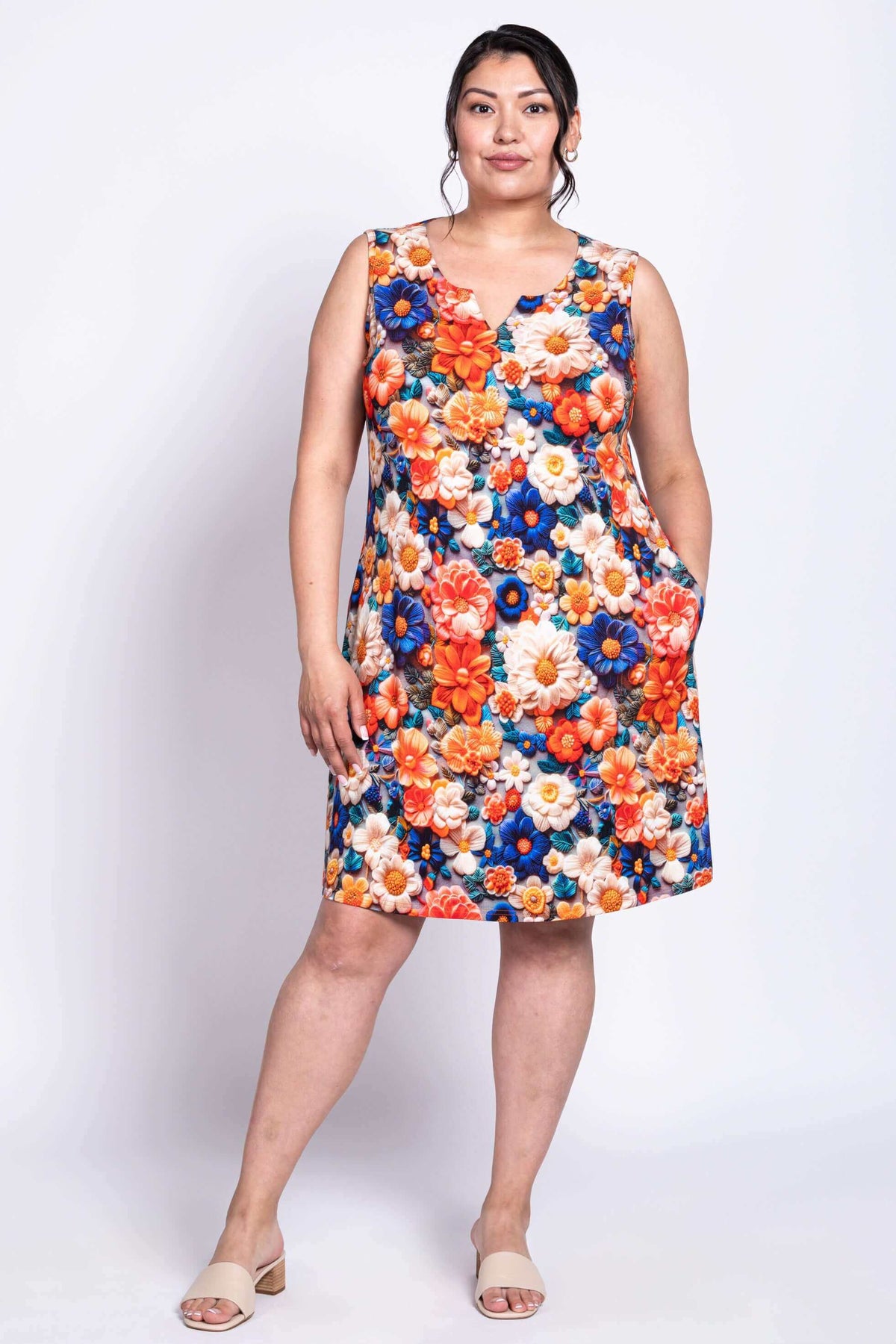 Woman modeling a sleeveless floral shift dress with pockets, facing slightly to the side