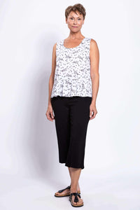 Woman modeling white bamboo linen tank top with peplum hem, angled front view