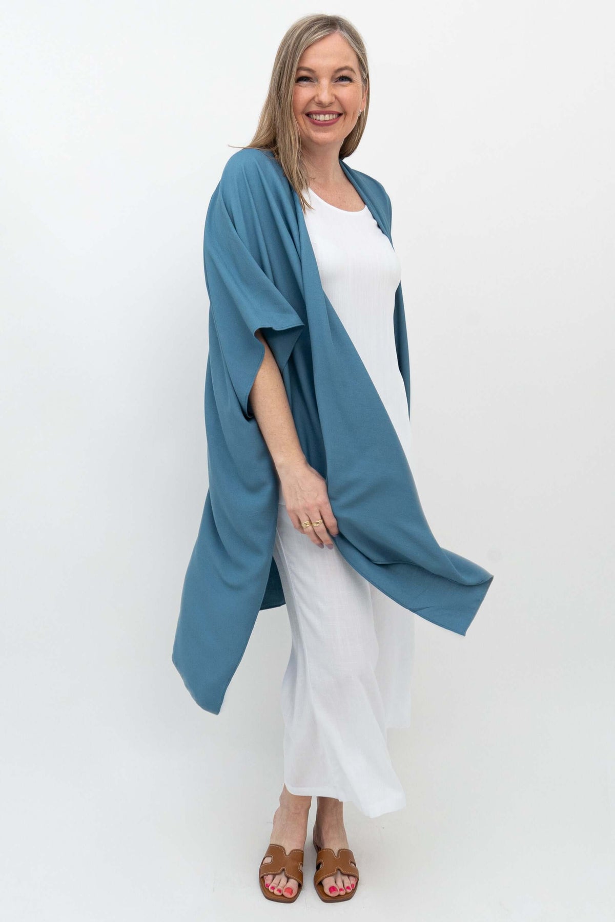 Woman in motion wearing an ocean blue Darcy kimono wrap, angled front view