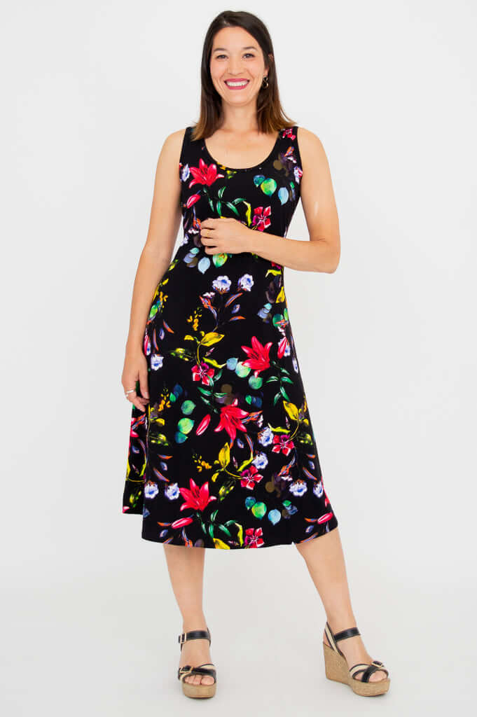 Woman smiling in black floral tank dress, hands on waist, slightly angled front view
