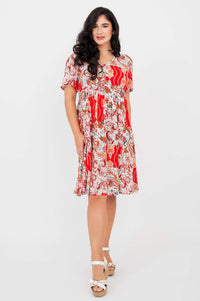 Model posing in a red and white empire waist dress with flutter sleeves, angled front view