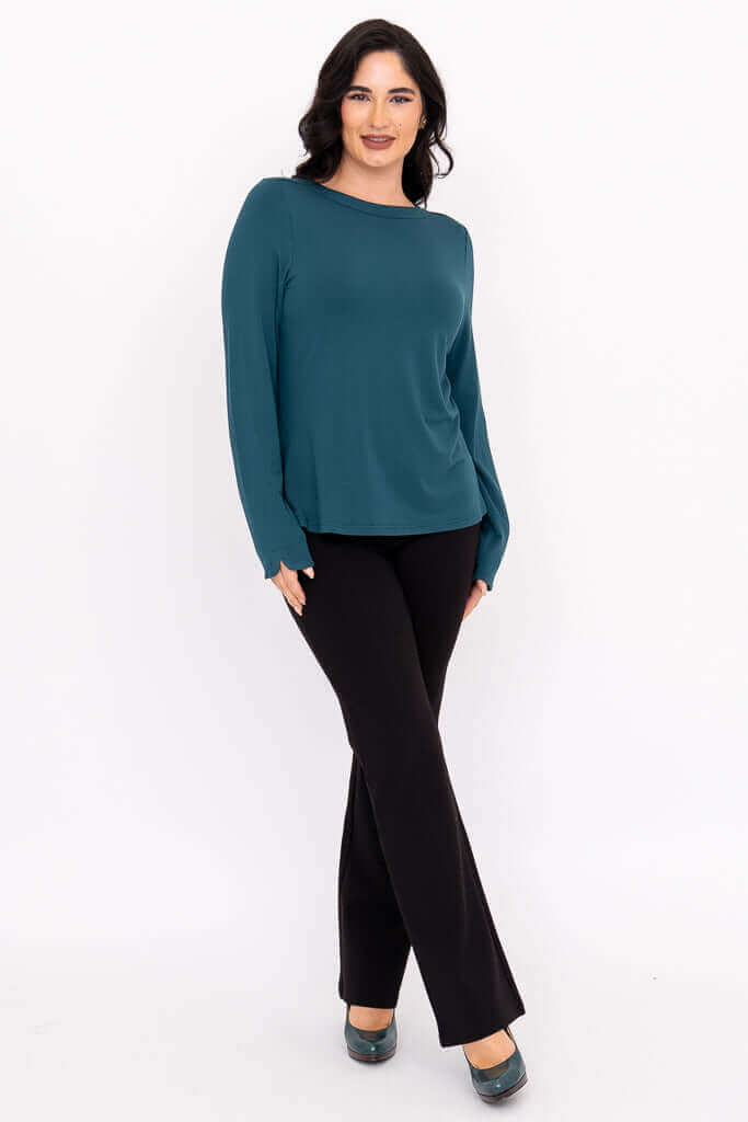 Angled front view of a woman modeling a teal boat neck top and black pants