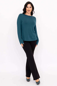 Angled front view of a woman modeling a teal boat neck top and black pants