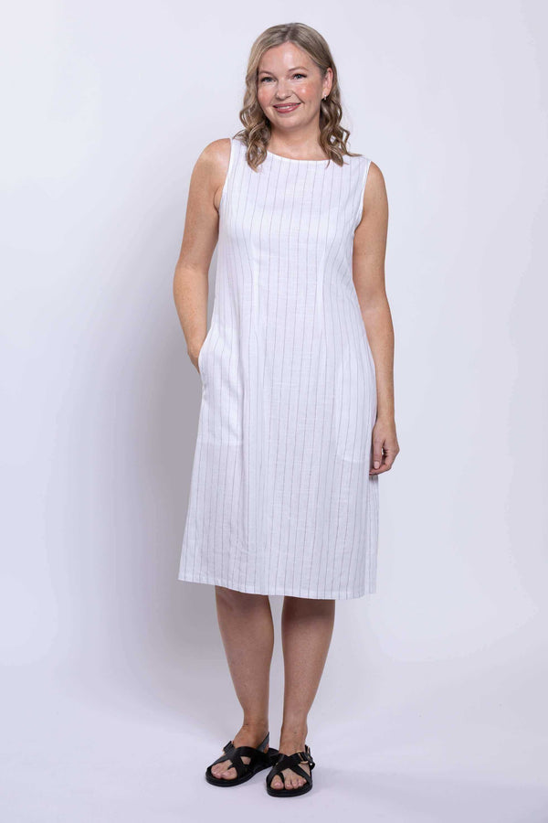 Front angled view of woman posing in a white sleeveless striped dress with pockets
