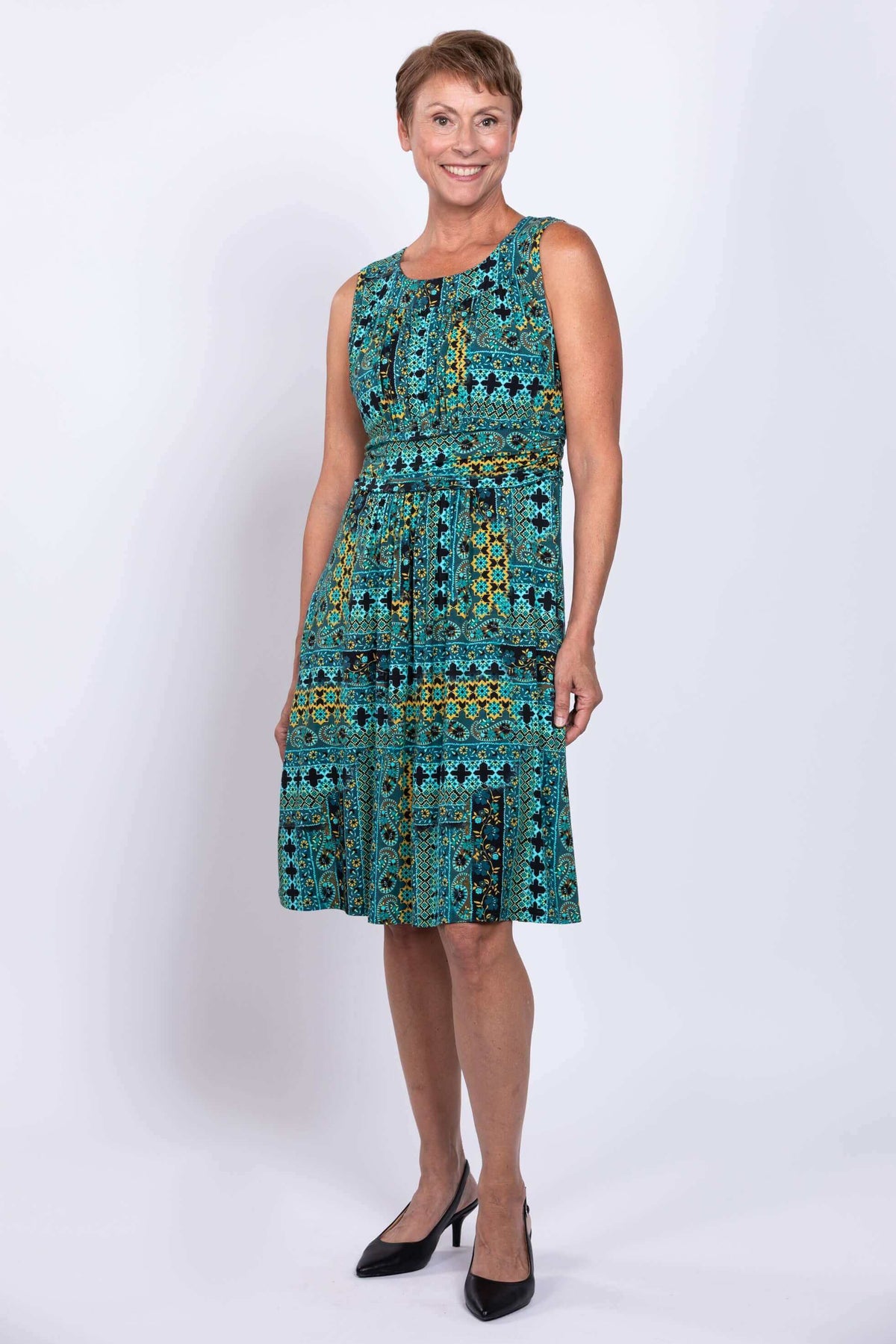 Woman posing in turquoise mosaic dress, angled front view