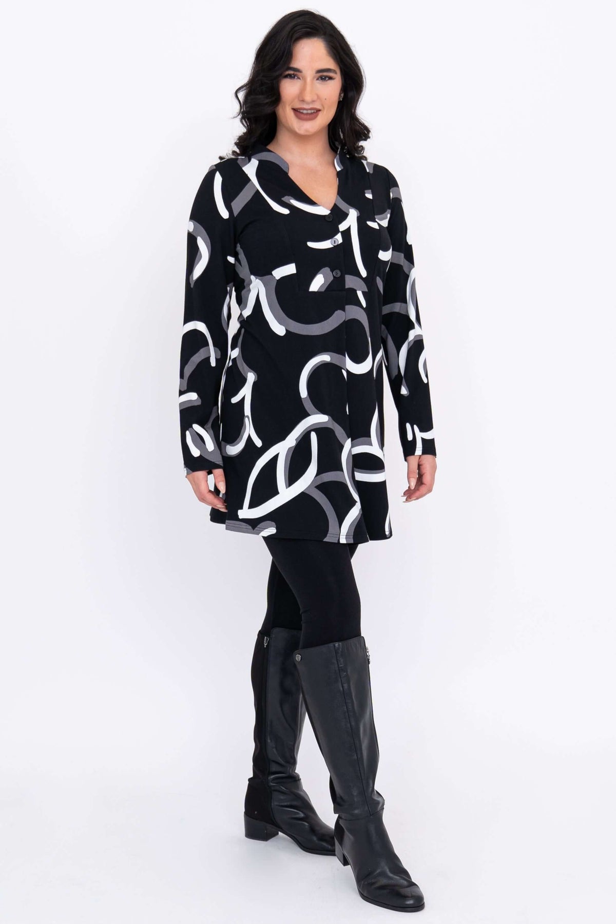 Angled view of Edwina tunic with bold abstract print, worn over leggings and boots.
