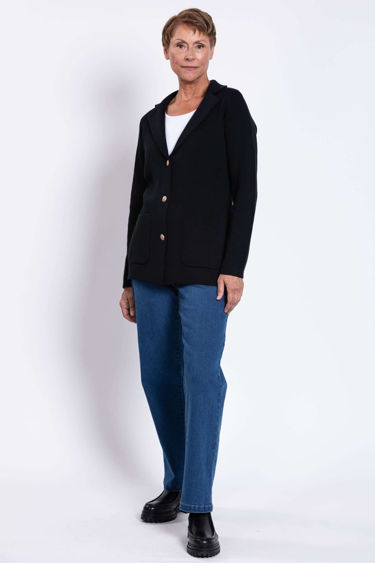 Angled full body view of a woman in the Margaret Jacket, styled with jeans and black boots