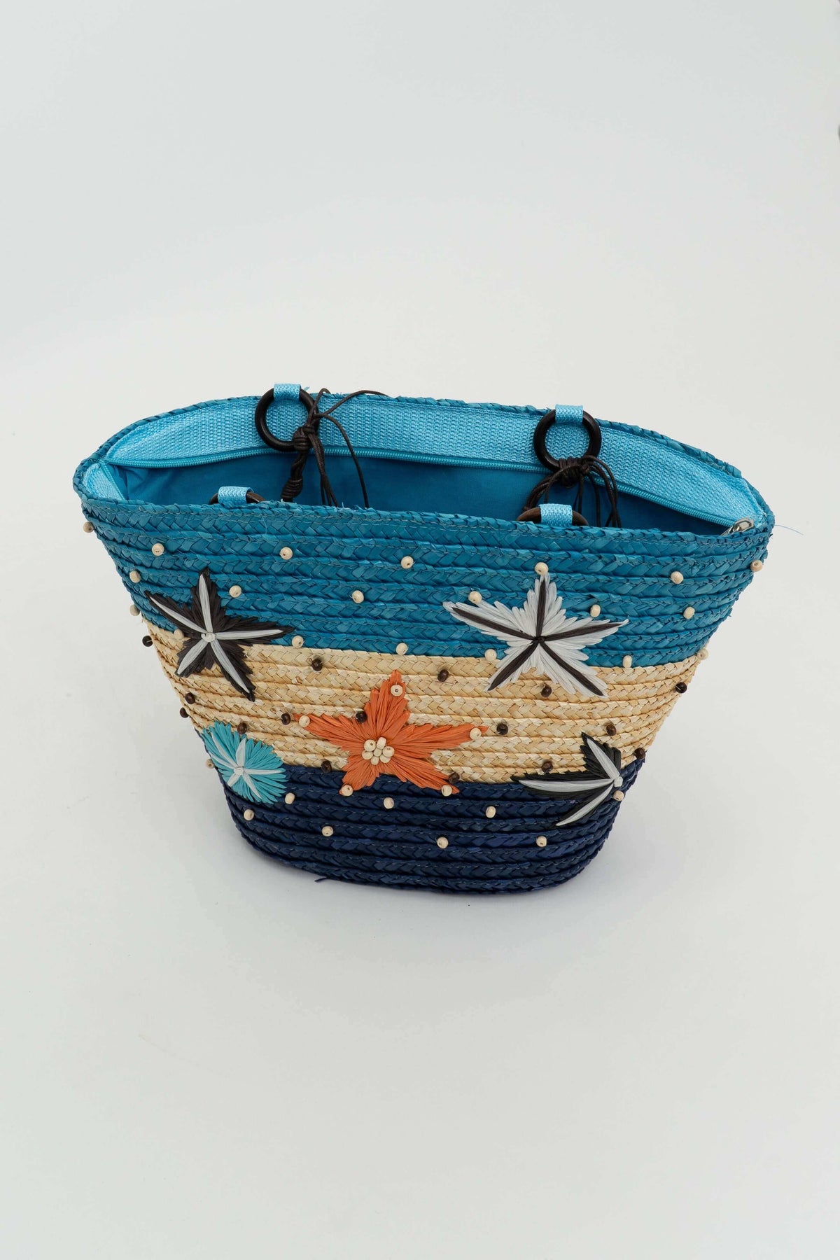 Angled view of multicolor rattan tote with decorative stars and beaded trim