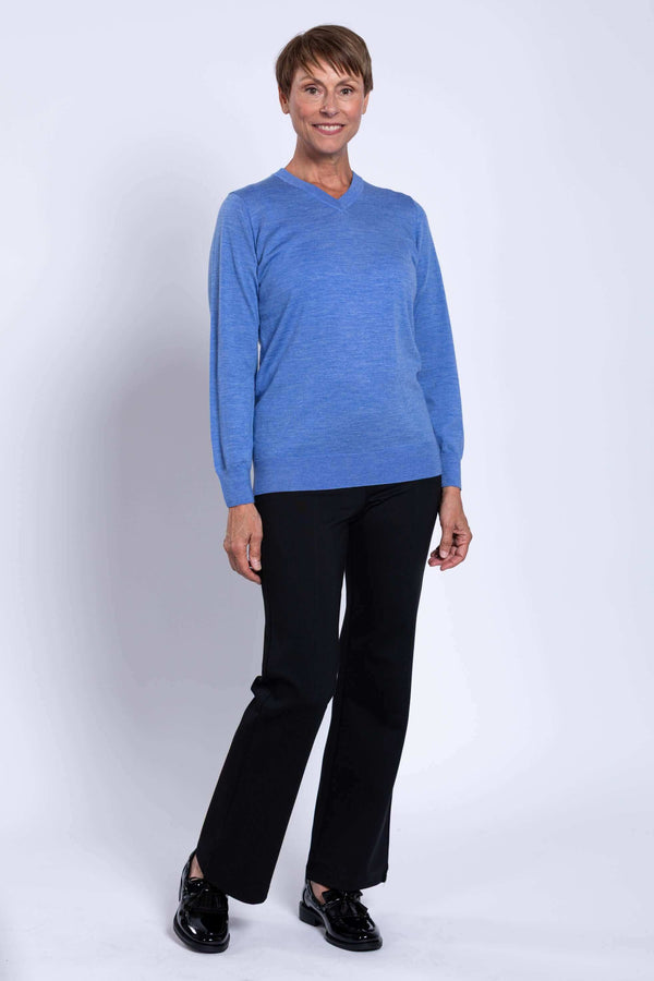 Woman in blue Merino V-neck sweater and black pants standing at an angle
