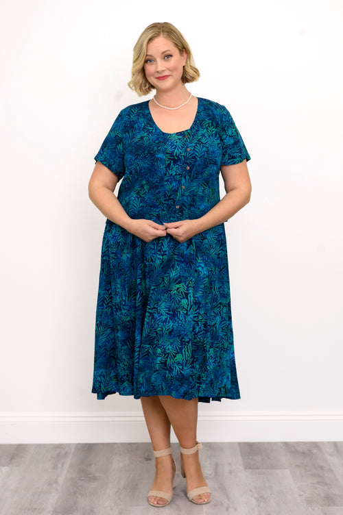 Woman wearing a blue patterned blouse and blue patterned dress against a white background, front view