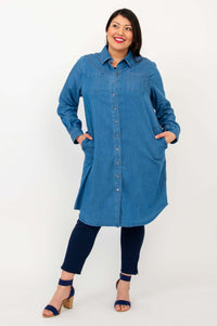 Woman standing with hands in pockets of blue Anka denim duster, showing front detail