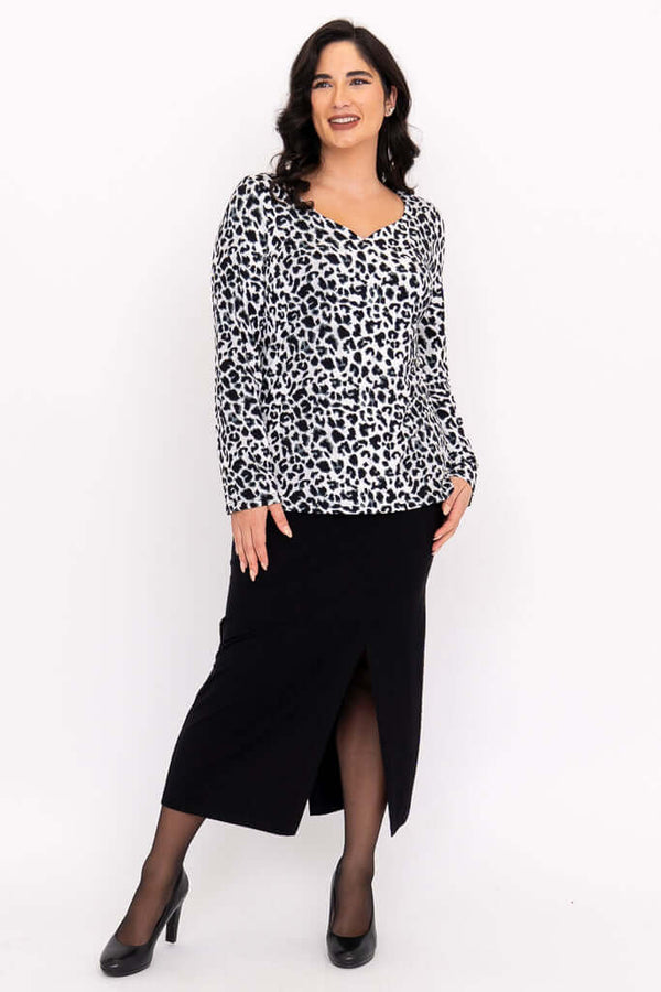 Model in Annette leopard print top and black skirt, standing and smiling